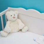 image de présentation de l'article accessoires lit bebe à ne pas oublier représentant un ourson blanc dans un lit à barreaux